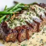 Garlic butter steak plated with Parmesan cream sauce, garnished and ready to serve.