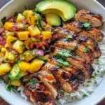 Jerk chicken bowl topped with mango salsa and coconut rice on a plate