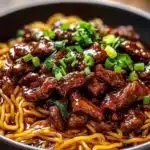 Delicious plate of sticky beef noodles garnished with fresh herbs