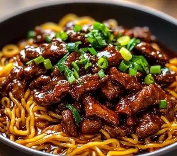 Delicious plate of sticky beef noodles garnished with fresh herbs