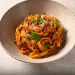 Delicious creamy Fettuccine Bolognese served in a bowl with fresh herbs