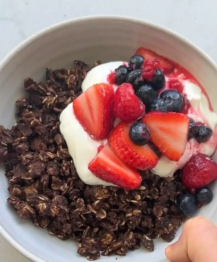 Bowl of chocolate scrambled oats topped with berries and nuts