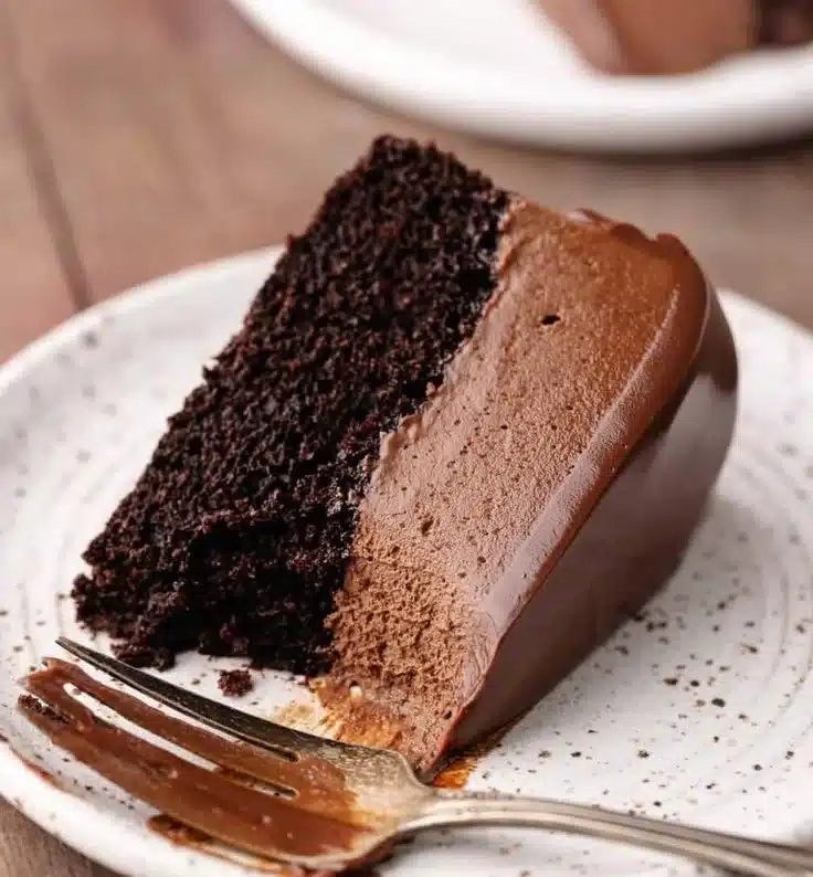 Slice of dark chocolate mousse cake topped with chocolate shavings and berries