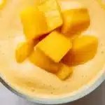 High-protein mango smoothie garnished with fresh mango slices and mint leaves