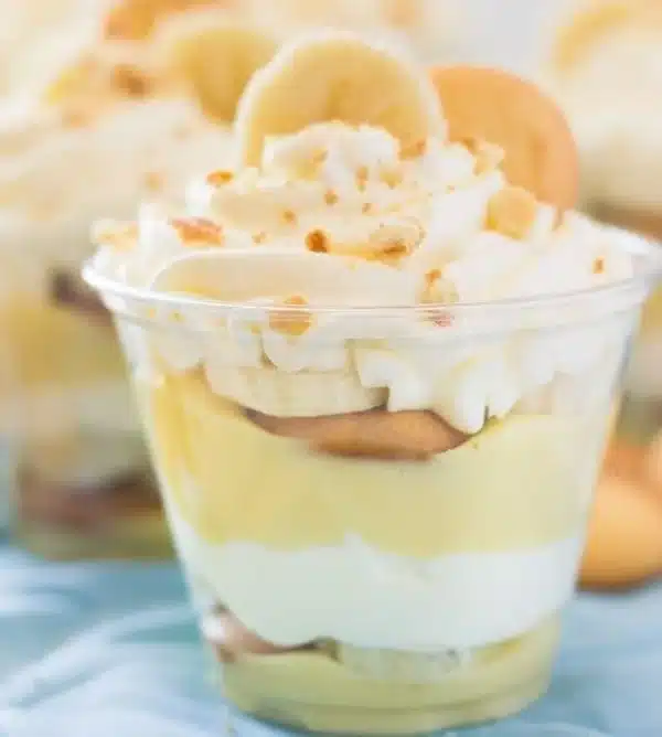 Delicious homemade banana pudding cups topped with whipped cream and banana slices.