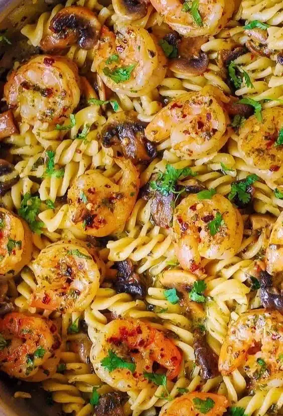 A bowl of pesto shrimp pasta topped with fresh shrimp and herbs