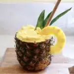 Freshly blended pineapple smoothie in a glass with tropical garnishes
