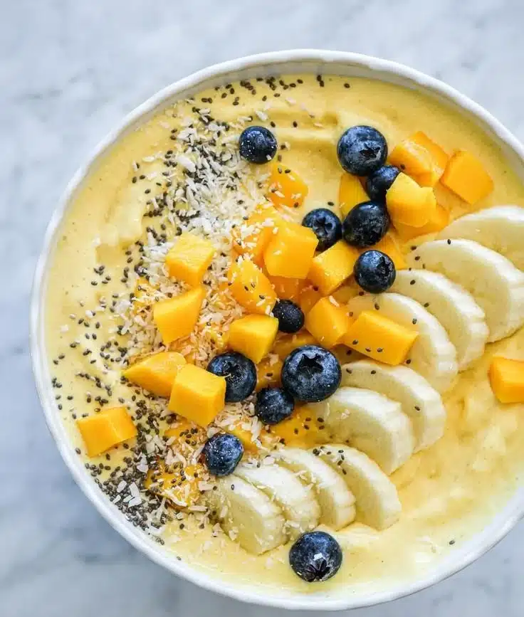 Colorful smoothie bowl topped with fresh fruits, nuts, and seeds.