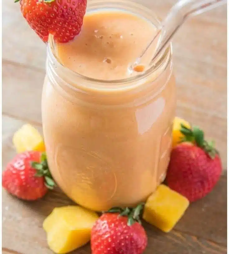Delicious strawberry mango smoothie in a glass with fresh fruit garnishes.