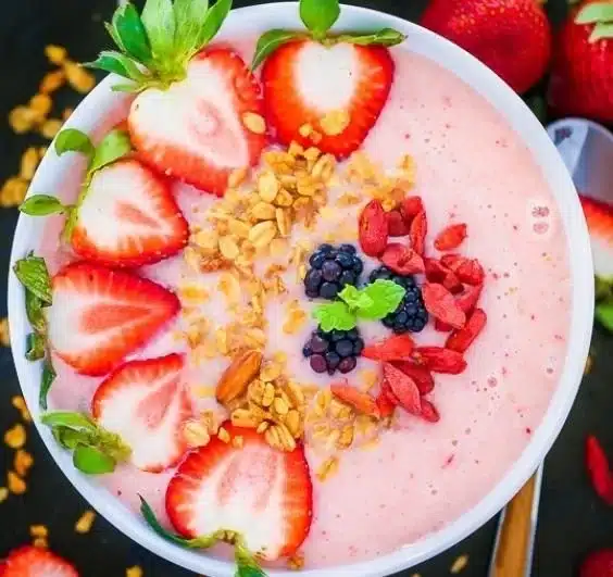 Strawberry pineapple smoothie bowl topped with fresh fruits and seeds
