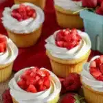 Delicious strawberry shortcake cupcakes topped with whipped cream and fresh strawberries.