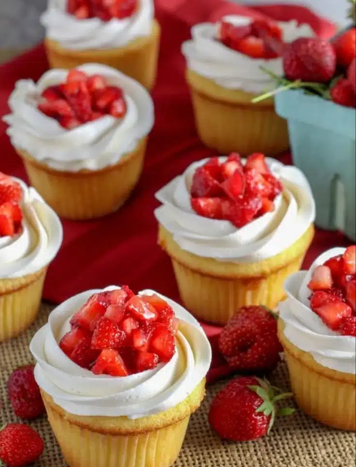 Delicious strawberry shortcake cupcakes topped with whipped cream and fresh strawberries.