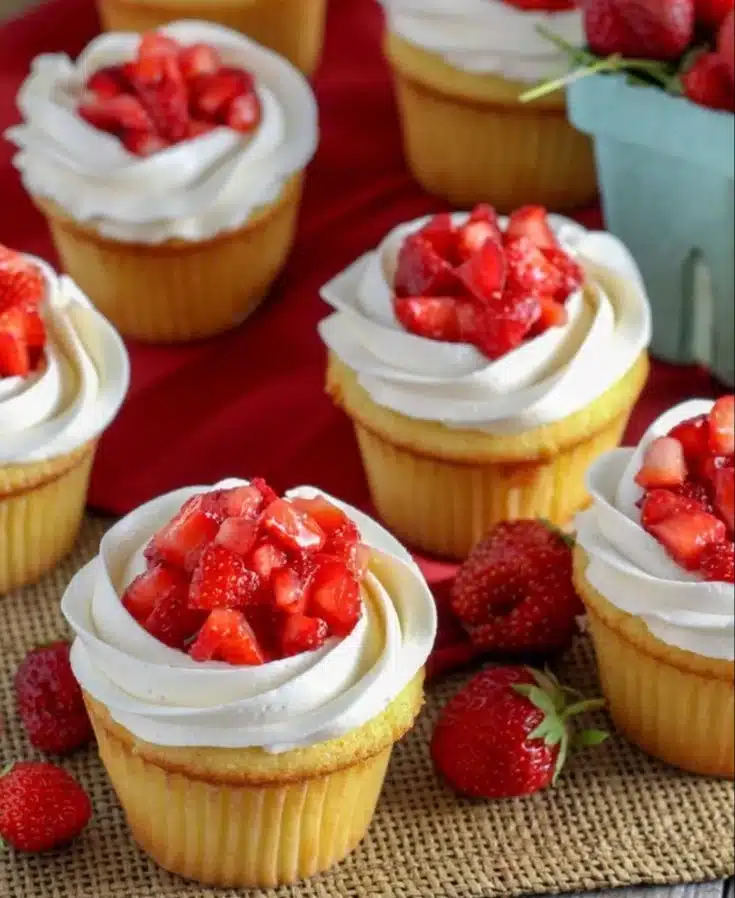 Strawberry shortcake cupcakes topped with fresh strawberries and whipped cream