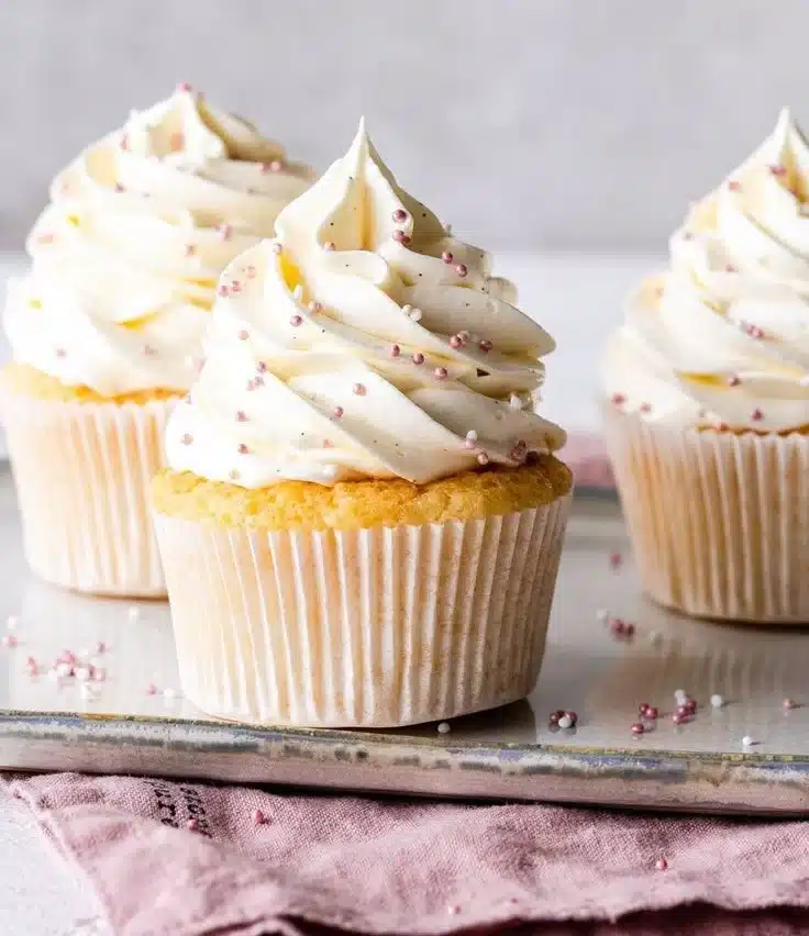 Delicious vanilla cupcakes topped with creamy frosting on a decorative platter.