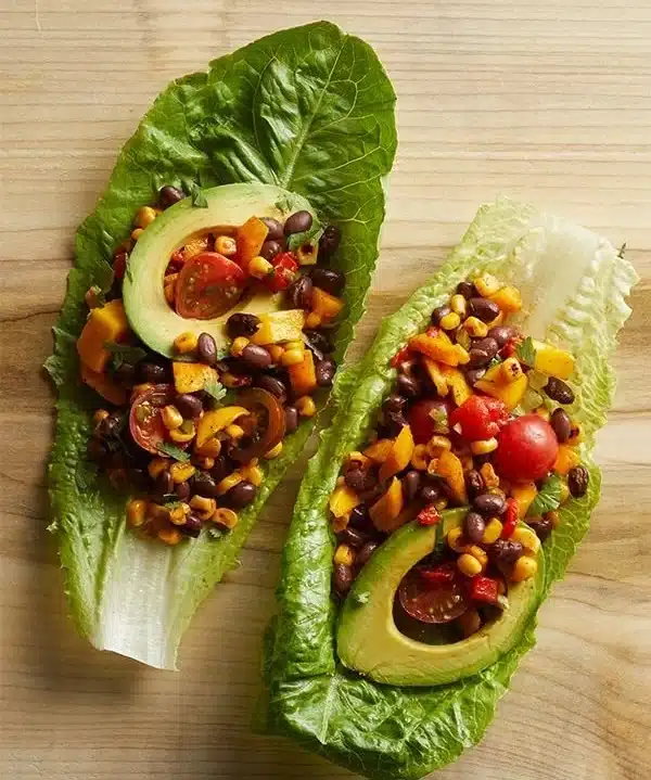 Vegan lettuce cups filled with colorful veggies and herbs on a plate.