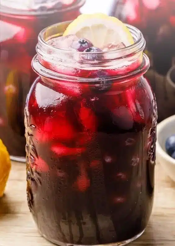 Glass of refreshing blueberry lemon iced tea garnished with fresh berries and lemon slices