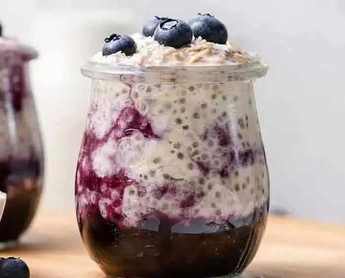 Bowl of blueberry overnight oats topped with fresh blueberries and mint