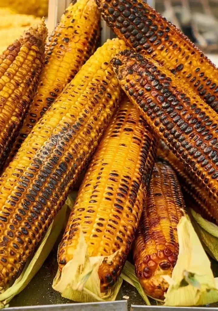 Delicious grilled corn on the cob garnished with herbs and spices.