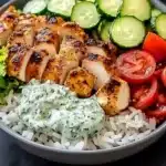 Mediterranean chicken bowl with fresh vegetables and herbs served in a colorful dish.