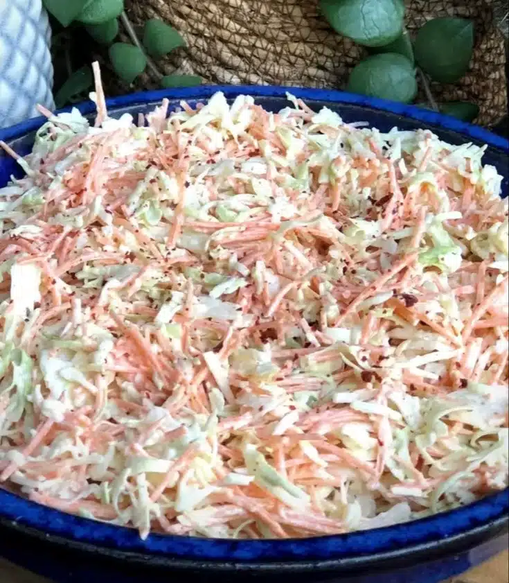 Bowl of simple coleslaw garnished with herbs for a fresh side dish