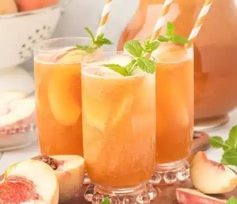 A glass of refreshing Southern Peach Tea with ripe peach slices on the side.